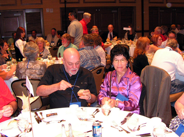 Terry Stuber - Denver Photos
Bill Kull attempts to perform surgery on a biscuit (not part of his MOS training) while spouse Linda smiles for the camera.
