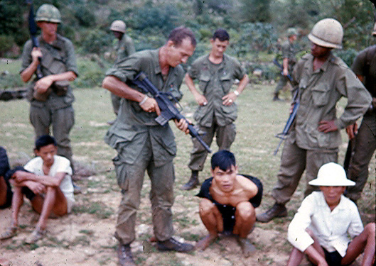 Lt Joe Wise, Plt Ldr for B/1/35, holds his weapon on a captured VC
