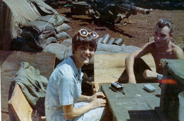 Chatting
One lucky redleg gets a personal interview.  Margi Ness is the Donut Dolly; she saw this photo and can't even remember ever wearing yellow sunglasses.  The intense next to Margi is "Mike".  I just noticed that this was our gun pit. You can see the muzzle of are 105mm in the back ground. It had the yellow paint job that the guy in the photo painted on it, Mike was a real character, he was  from CA., LA I think. He was a real Head if you catch my drift. Not that we were angels by any means but he was really out there and then some. One intense guy if you look at him talking to the Dolly. Oh well what can I say. We all had our quirks.   (Note: see the howitzer in the rear...it's wheels were removed because they were a nuisance when traversing the weapon.
