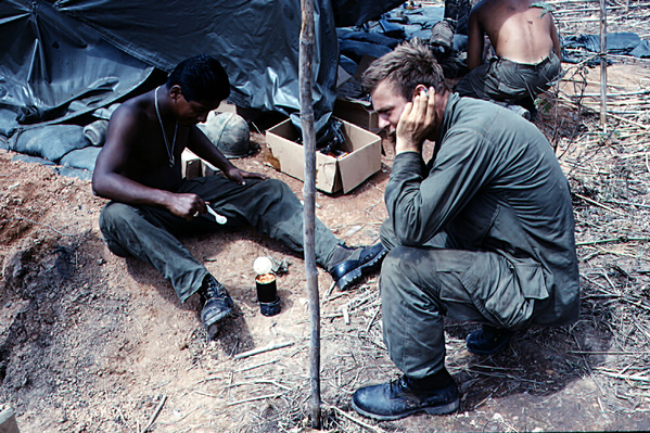 C-Rats
All field troops knew the trick of using one C-rat can as a "mini-stove" and heating an otherwise cold can of rations.  Note the improvised bedding of sand bags and an air mattress. Everyone, I'm sure, is familiar with the white plastic spoons.
