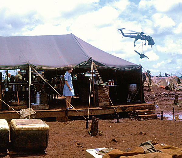 Curious
Another Donut Dolly (Linda) observes a Sikorsky Sky Crane haul a 105mm howitzer.  Jenny believes this photo may have been taken at LZ Highlander Heights, Mary Lou or Bison, but definitely in the 4th Inf Div Area of Operations.
