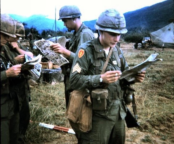 Waiting for a Huey
The Survey Crew is waiting on a ride, reading the Stars and Stripes while Sgt Barrington studies the map of our soon-to-be survey area.  More than likely, it was the caves in the Hon Noc mountains.
