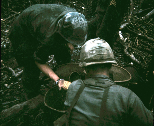 Destroying the caves
Soldiers of B/1/14 checking out a rice cache retrieved from the caves.  The soldier named Logan has his name marked on the top of his helmet.  His partner has the name "Bart" on the neck of his webgear.
