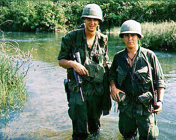 Think this path may be flooded
FO Lt Wayne Crochet stands knee-deep in a stream with "Poncho", the Company Commander's RTO.  One way to "cool your dogs" and wash your boots at the same time.

Photo courtesy of Cliff "Westy" Westwood of B/2/35
